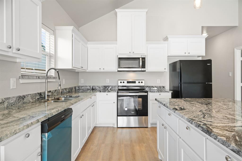 2306 Church Street Greenville, TX 75401 - Photo 11 of 24 a kitchen with kitchen island granite countertop a sink stainless steel appliances and white cabinets