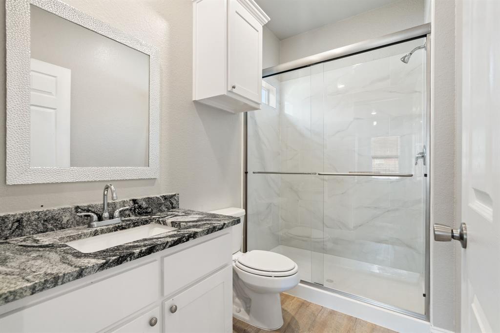 2306 Church Street Greenville, TX 75401 - Photo 15 of 24 a bathroom with a granite countertop sink toilet and shower