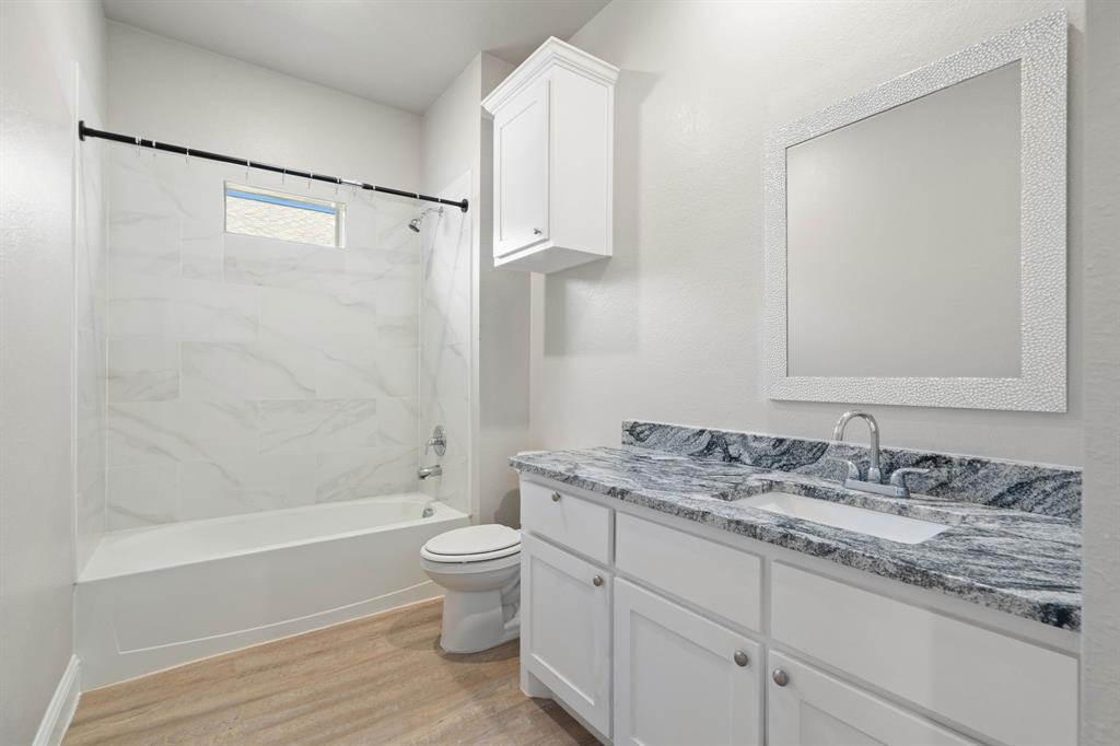 2306 Church Street Greenville, TX 75401 - Photo 18 of 24 a bathroom with a granite countertop sink toilet and shower