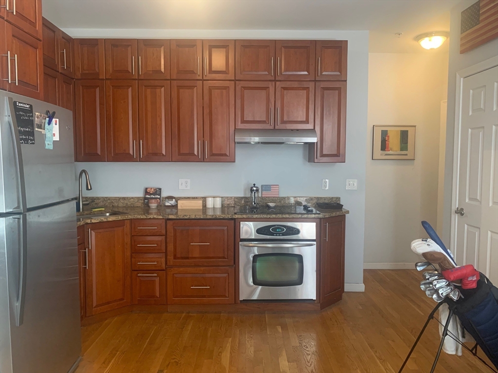 483 Beacon Street, Unit 26 Boston, MA 02115 - Photo 2 of 9 a kitchen with stainless steel appliances granite countertop a stove a refrigerator and a wooden cabinets