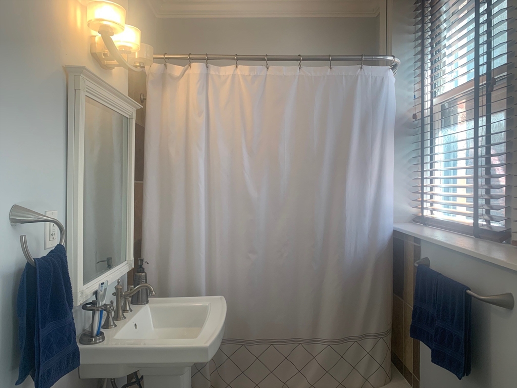 483 Beacon Street, Unit 26 Boston, MA 02115 - Photo 7 of 9 a bathroom with a sink a mirror and a shower curtain