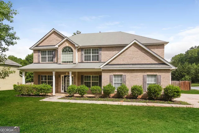 a front view of a house with a yard and trees
