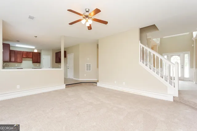 a view of an empty room with kitchen and a window