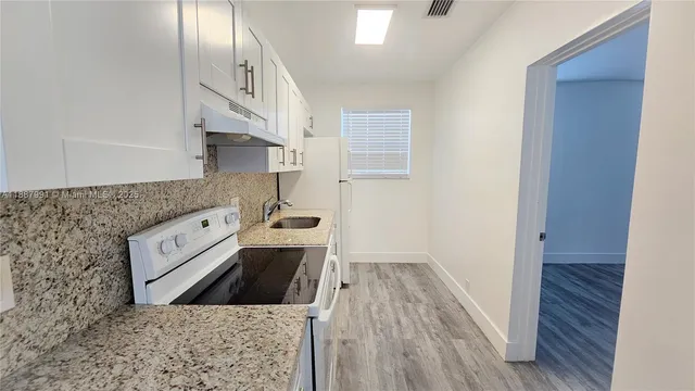 a kitchen with stainless steel appliances granite countertop a refrigerator a stove and a wooden floors