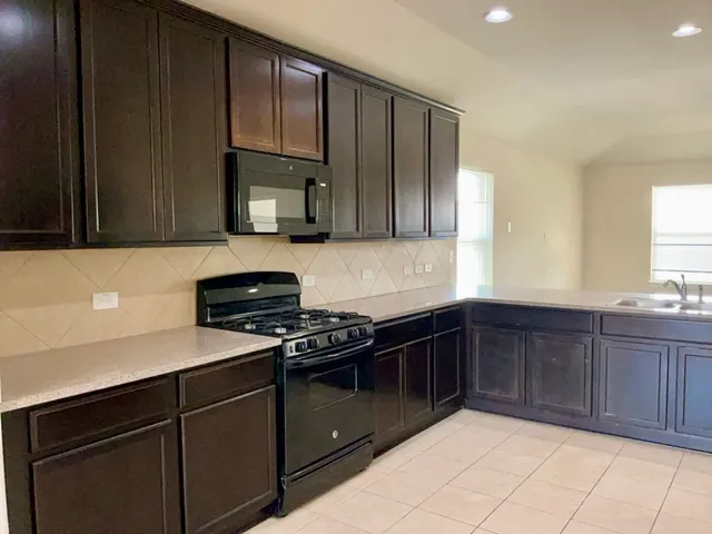 a kitchen with granite countertop wooden cabinets and a stove top oven