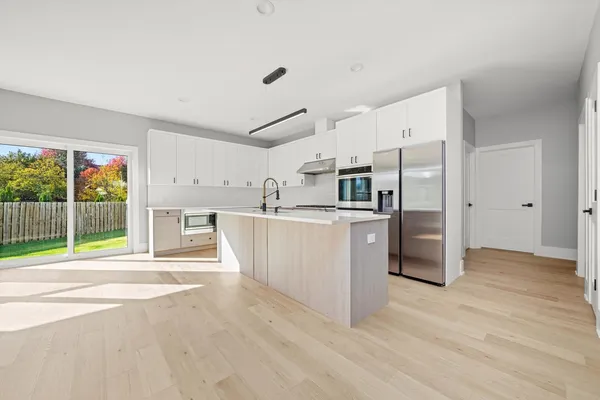 a large white kitchen with stainless steel appliances a large counter top and a wooden floors