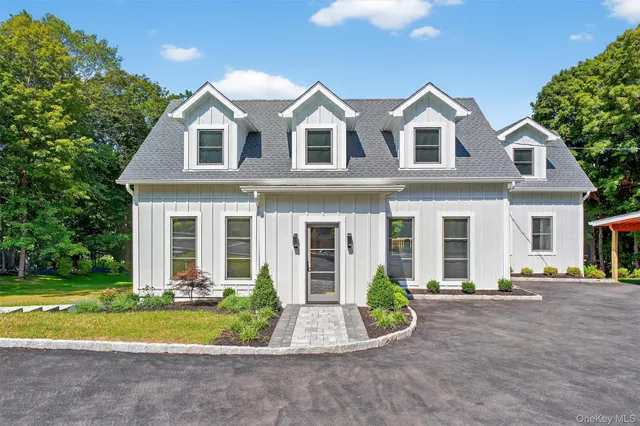 a view of a white house with large windows and a large tree