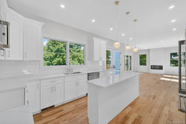 a large white kitchen with kitchen island granite countertop a large window
