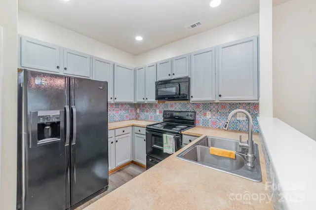 a kitchen with stainless steel appliances granite countertop a refrigerator a stove top oven a sink and dishwasher