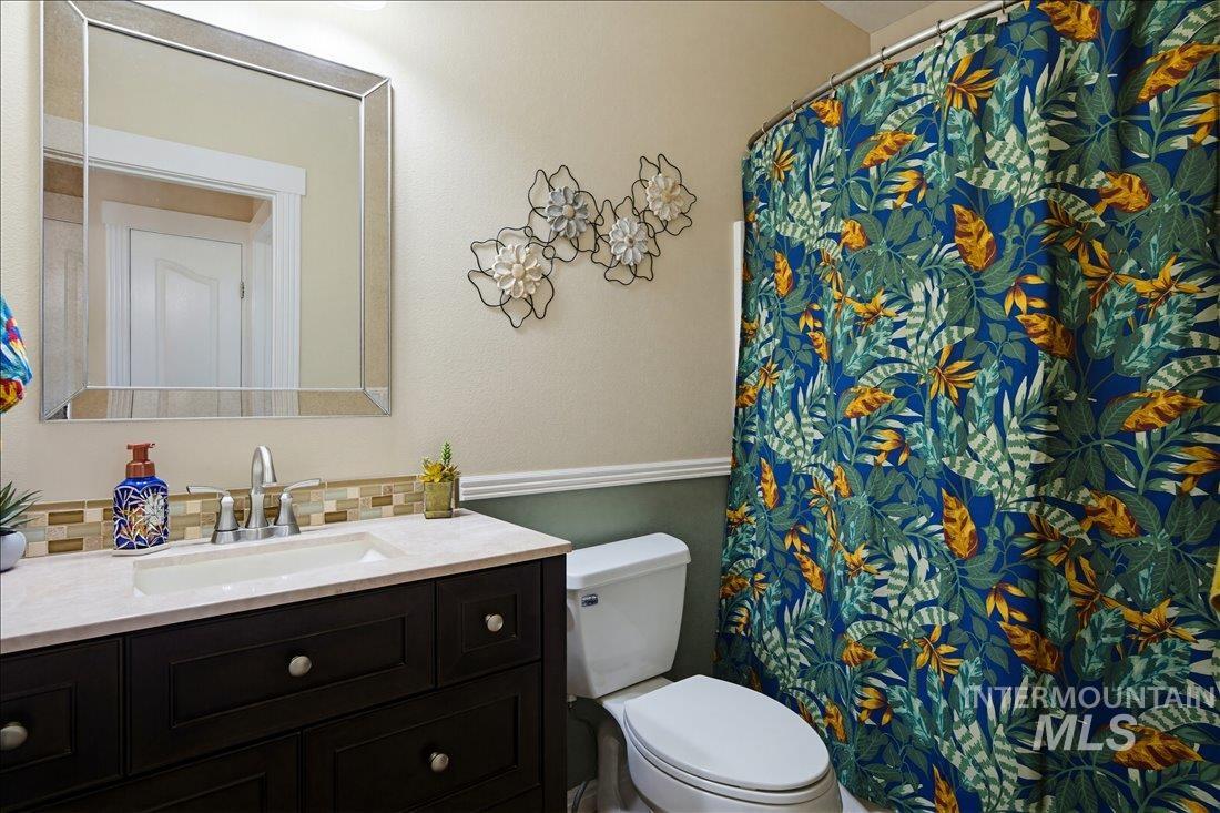 24623 Falcon Lane Caldwell, ID 83607 - Photo 14 of 40 Bathroom featuring a dark wood-finish vanity with a light-colored countertop, an undermount sink, and a mirrored wall-mounted cabinet