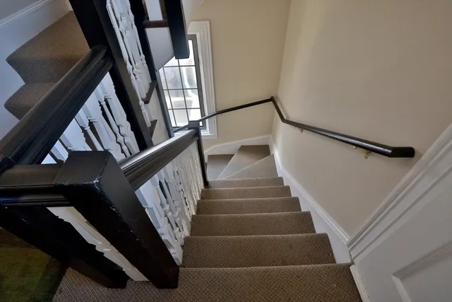 a view of staircase with railing and white walls