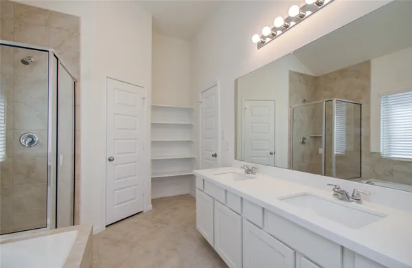 a spacious bathroom with a double vanity sink a large mirror and shower