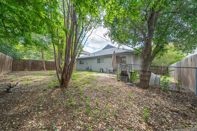 a view of a house with a yard and large tree