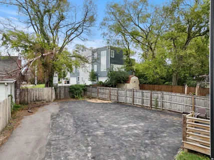 a view of a white house with a large tree and wooden fence