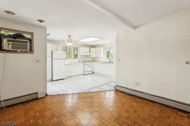 a kitchen with granite countertop white cabinets white appliances a sink and a window