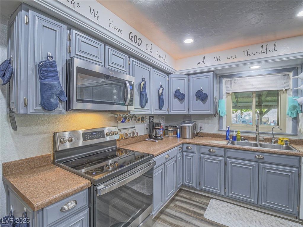 846 Fairview Drive Henderson, NV 89015 - Photo 18 of 39 Kitchen with appliances with stainless steel finishes, dark wood finished floors, gray cabinets, a textured wall, and blue cabinets