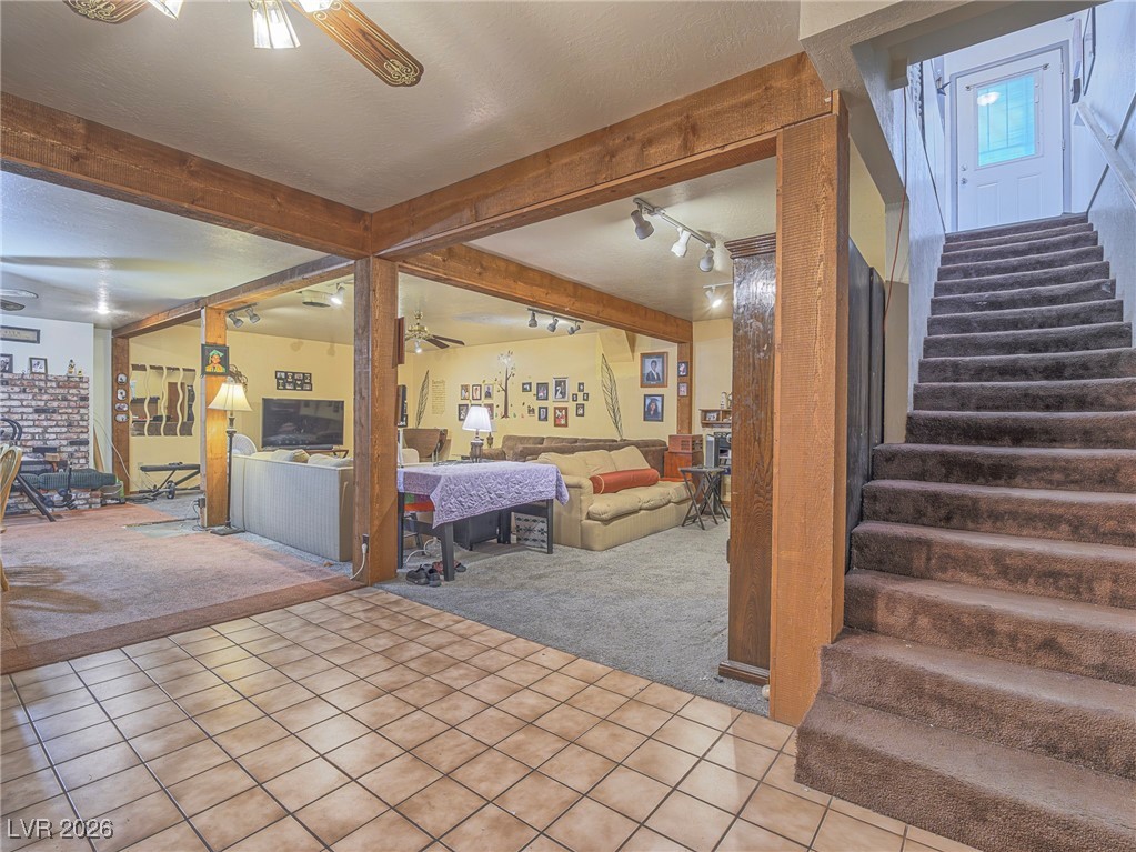 846 Fairview Drive Henderson, NV 89015 - Photo 27 of 39 Carpeted living area with ceiling fan, stairs, tile patterned floors, beam ceiling, and track lighting