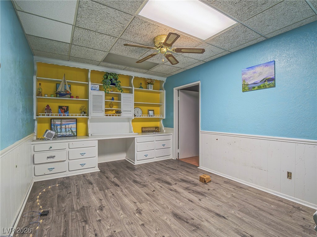 846 Fairview Drive Henderson, NV 89015 - Photo 32 of 39 Office area featuring built in desk, a textured wall, wainscoting, dark wood-type flooring, and ceiling fan