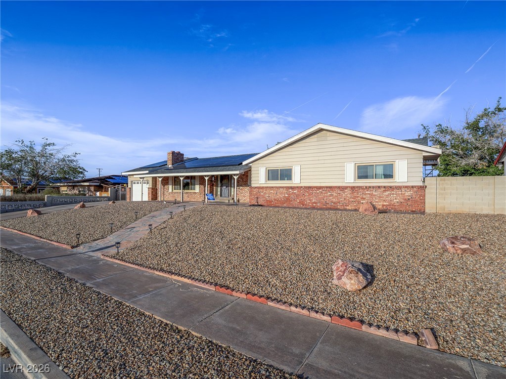 846 Fairview Drive Henderson, NV 89015 - Photo 9 of 39 Ranch-style home with roof mounted solar panels, a porch, brick siding, and a chimney