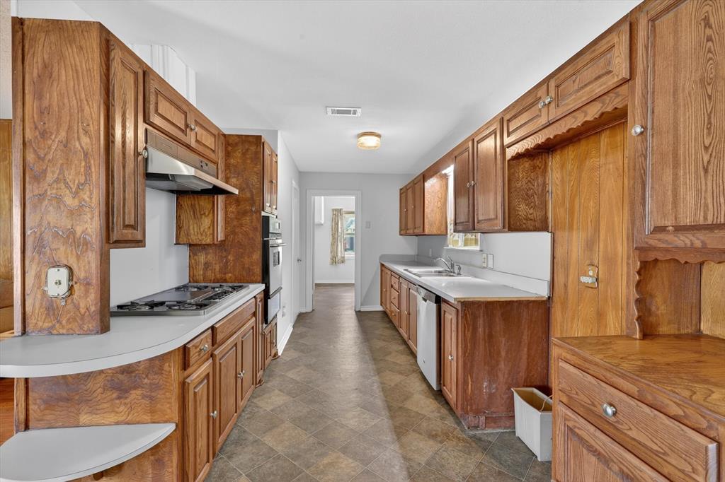 624 North Ave A Springtown, TX 76082 - Photo 11 of 29 a kitchen with granite countertop stove top oven sink and cabinets