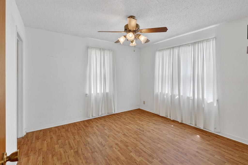 624 North Ave A Springtown, TX 76082 - Photo 20 of 29 an empty room with wooden floor chandelier fan and windows