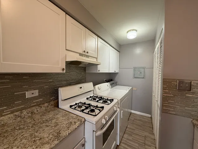 a kitchen with granite countertop a stove a sink and a refrigerator