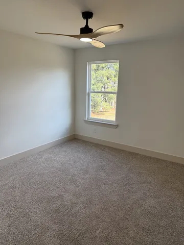 an empty room with windows and ceiling fan