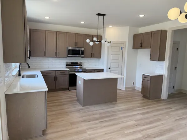 a large kitchen with stainless steel appliances kitchen island granite countertop a stove and a refrigerator