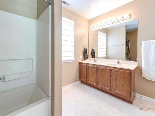 a bathroom with a double vanity sink mirror and bathtub