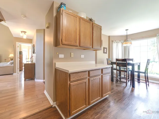 a kitchen with a table chairs refrigerator cabinets and wooden floor