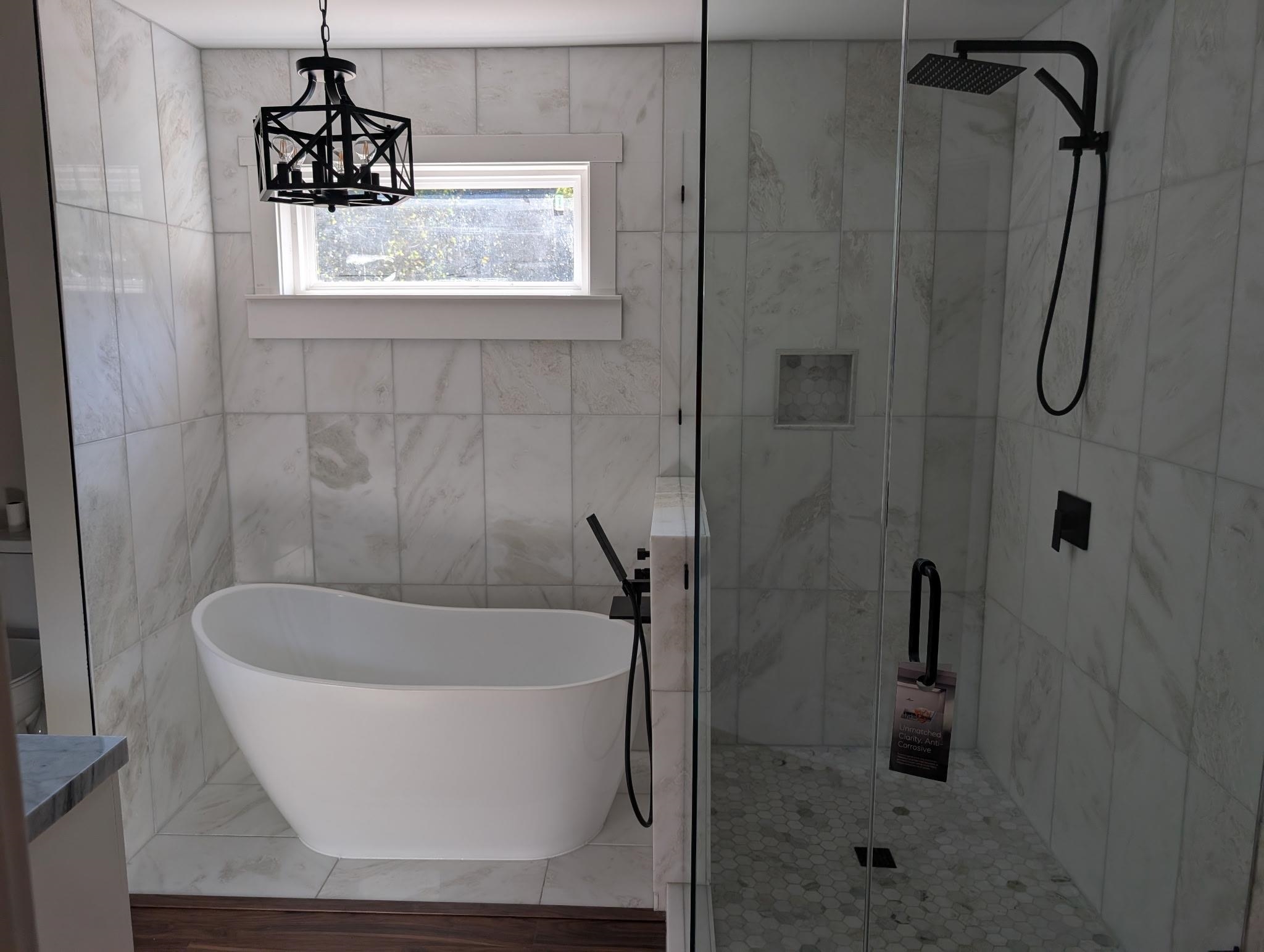 3540 Portersville Road Atoka, TN 38004 - Photo 18 of 37 Freestanding soaking tub, walk-in shower with glass enclosure, rain showerhead, square floor tiles, and wood-finish flooring