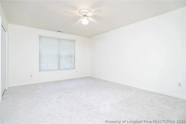 an empty room with a ceiling fan and a window