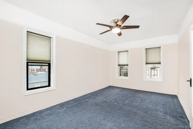 an empty room with a window and a ceiling fan