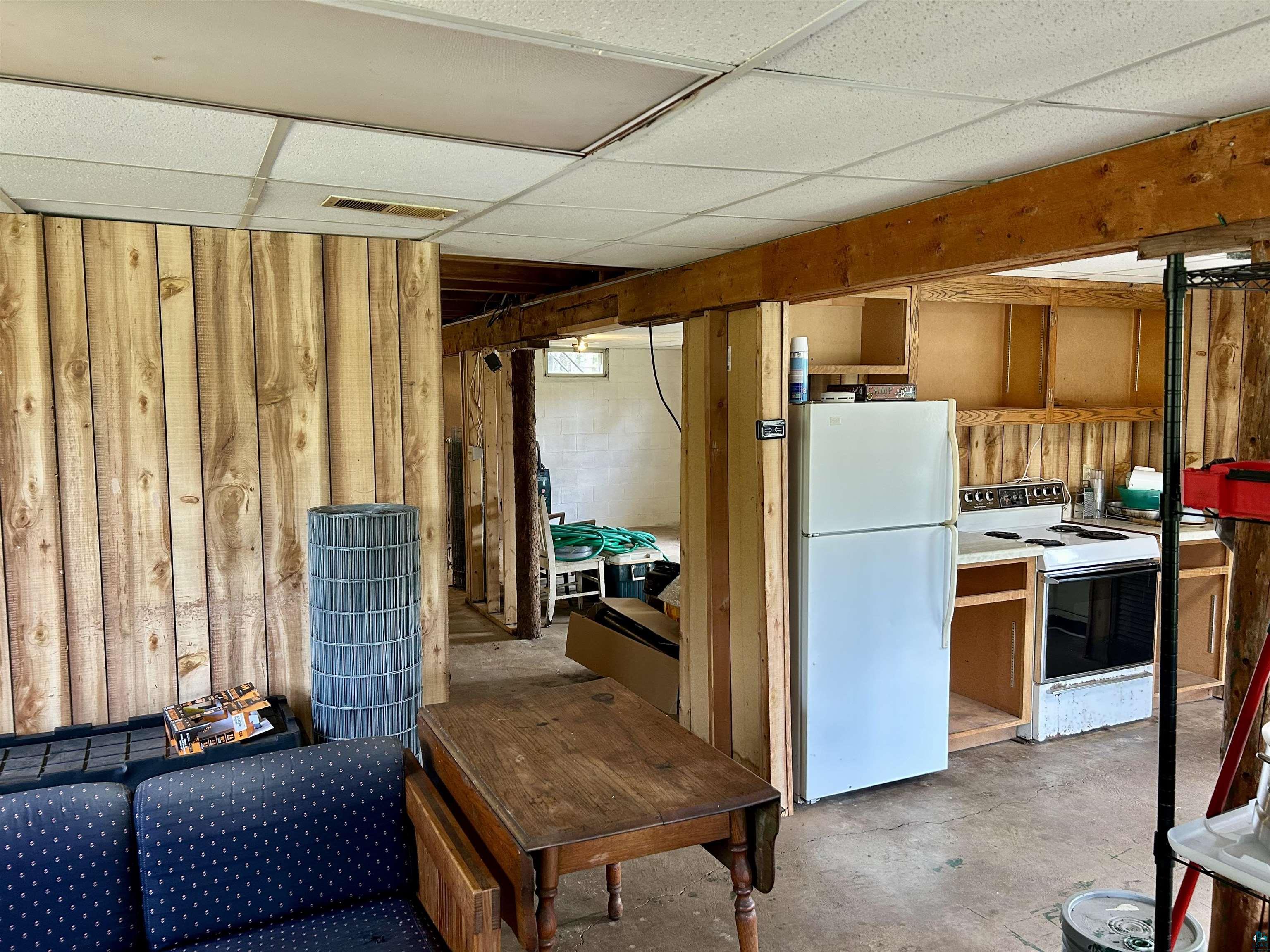4184 Bergstrom Road Two Harbors, MN 55616 - Photo 7 of 20 Below grade area featuring freestanding refrigerator, a paneled ceiling, and wooden walls