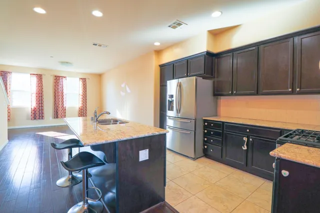 a kitchen with stainless steel appliances granite countertop a refrigerator a sink dishwasher a stove with wooden cabinets and wooden floor