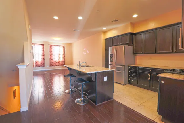 a kitchen with stainless steel appliances granite countertop a refrigerator a sink dishwasher and a stove with wooden floor