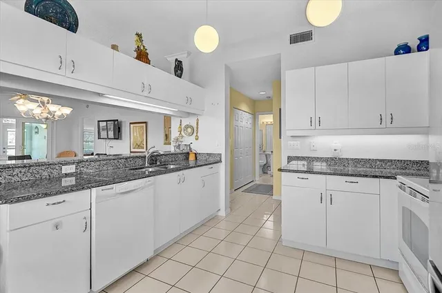 a kitchen with granite countertop a white cabinets and white stainless steel appliances
