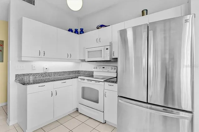 a dining hall with stainless steel appliances granite countertop a stove a sink a dining table and chairs with wooden floor