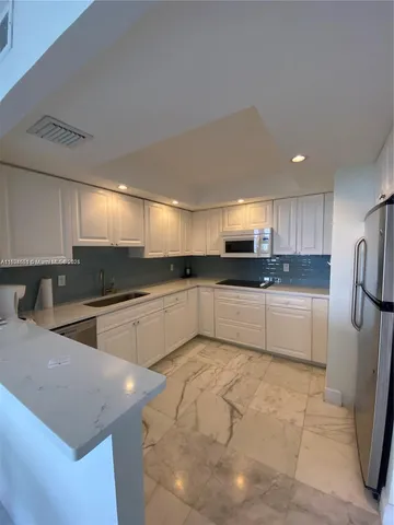a large white kitchen with a sink and refrigerator