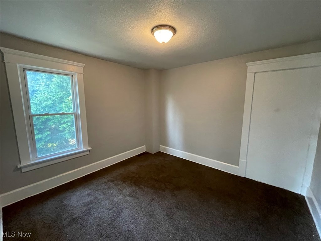 950 Avon Street Akron, OH 44310 - Photo 9 of 15 Unfurnished room featuring baseboards, dark carpet, and a textured ceiling