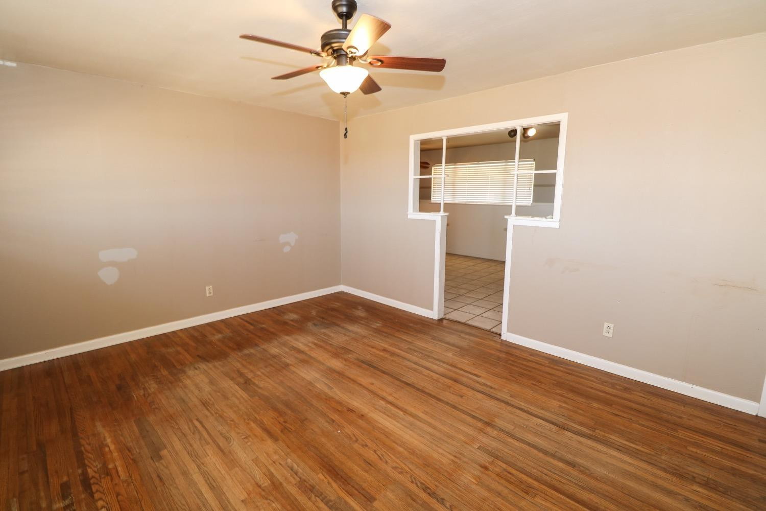 450 County Road 29 Muleshoe, TX 79347 - Photo 3 of 27 an empty room with wooden floor chandelier fan and windows