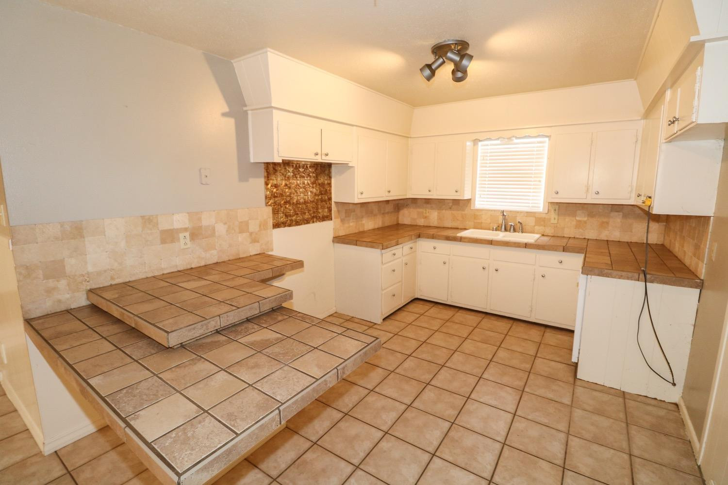 450 County Road 29 Muleshoe, TX 79347 - Photo 6 of 27 a kitchen with a sink a stove and white cabinets with wooden floor