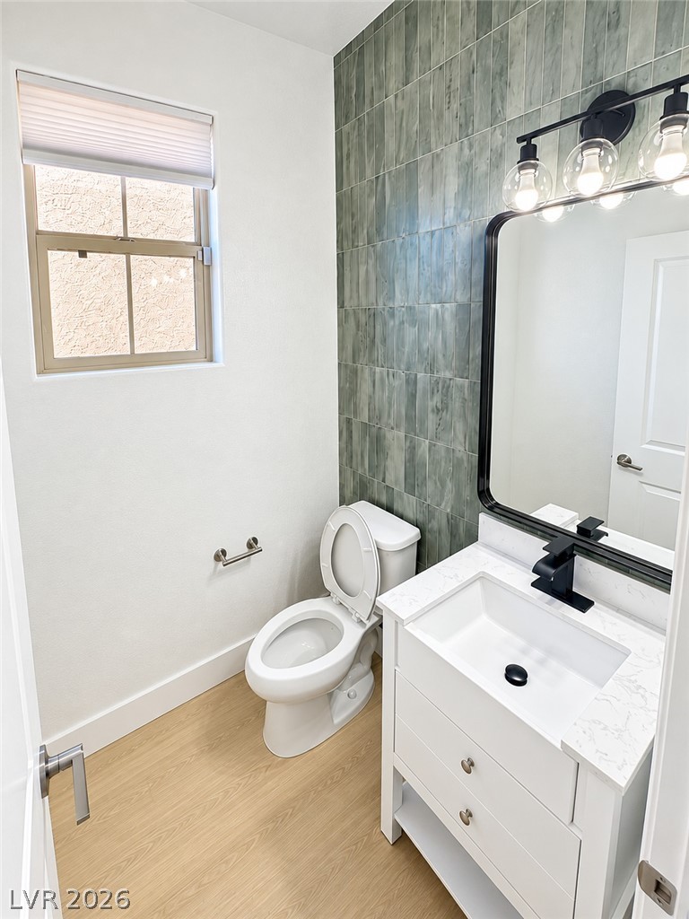 Vertical tiling and wood-look flooring enhance this contemporary powder room.