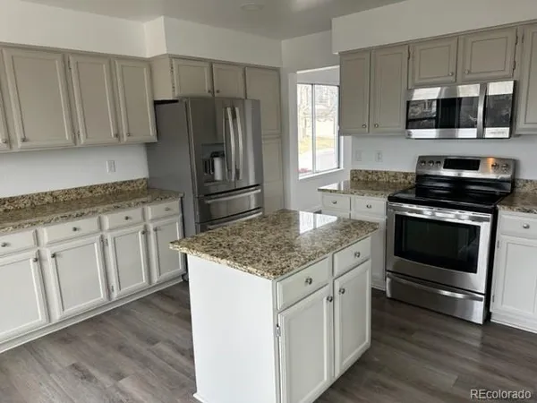 a kitchen with stainless steel appliances granite countertop a stove microwave and refrigerator