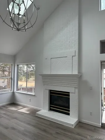 a view of an empty room with wooden floor fireplace and a window
