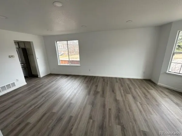 an empty room with wooden floor and windows