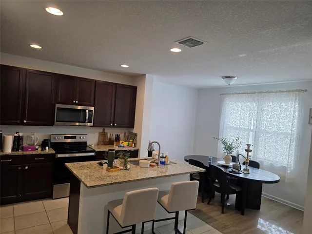 a kitchen with a sink a microwave a refrigerator and chairs