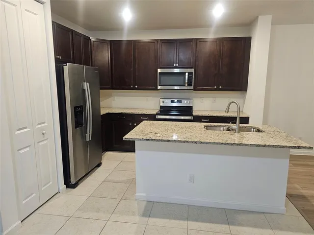 a kitchen with granite countertop a refrigerator and a stove top oven