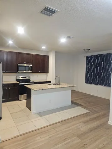 a kitchen with stainless steel appliances granite countertop a stove a sink and a microwave