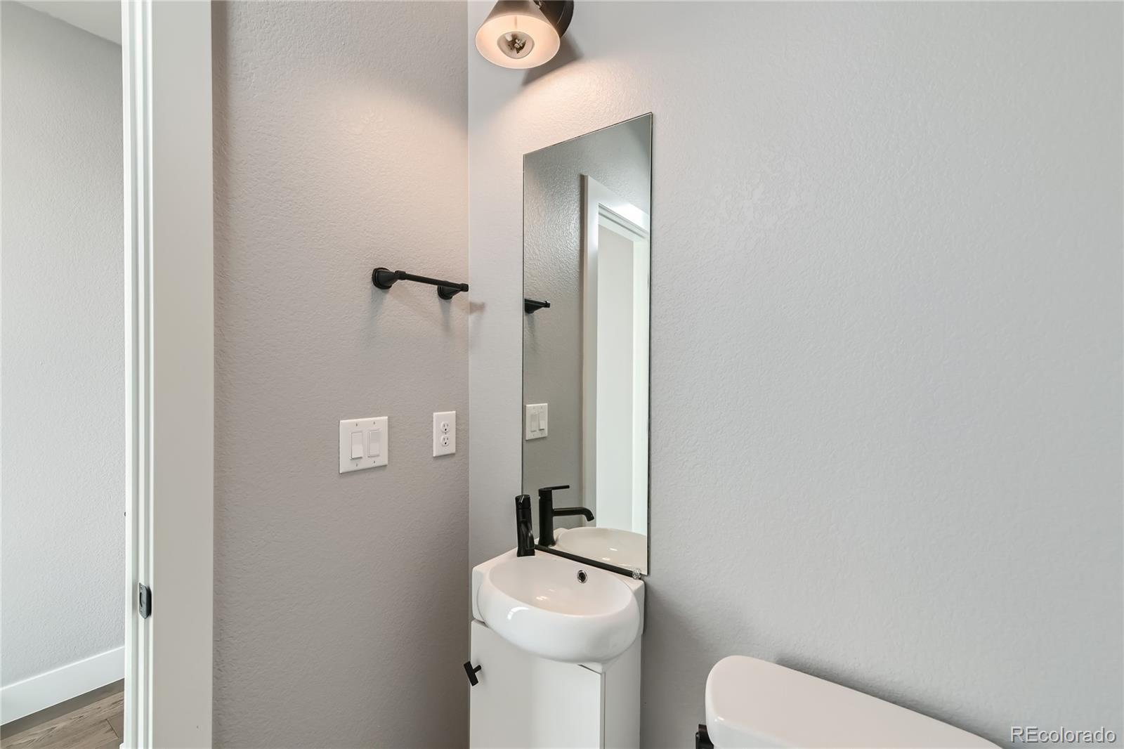 1284 Stuart Street Denver, CO 80204 - Photo 7 of 43 a bathroom with a toilet a sink and mirror